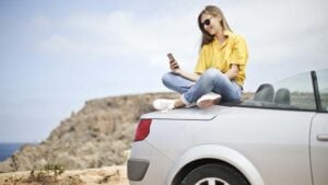 a girl sitting on a car buying a Car Insurance in Spain