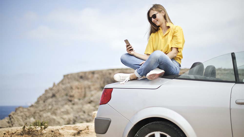 a girl sitting on a car buying a Car Insurance in Spain