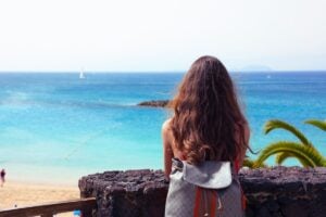 Young woman with backpack looking to La Playa de Papagayo, Lanzarote, Canary Islands