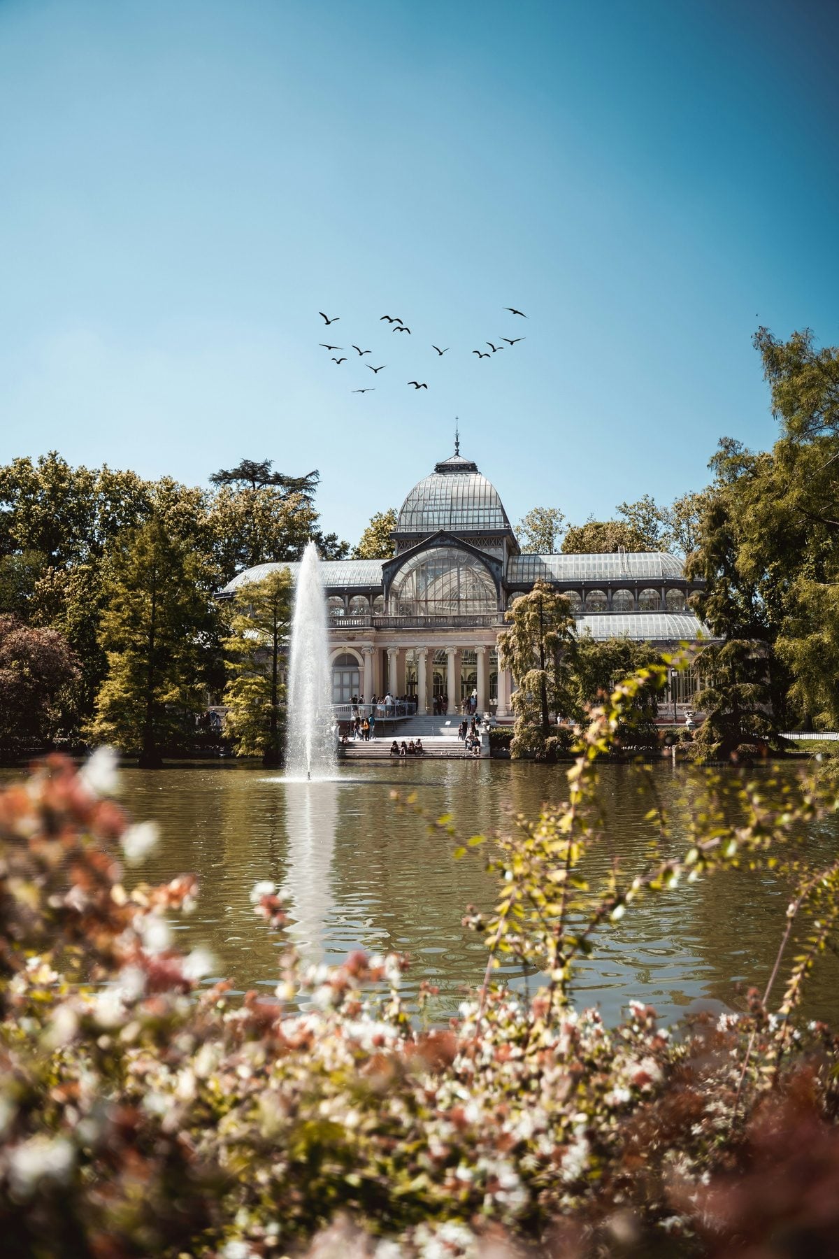 Palacio de Cristal glass pavilion reflected in the lake at Retiro Park in central Madrid