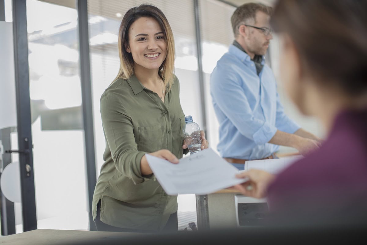 An immigration lawyer handing a client their visa application.