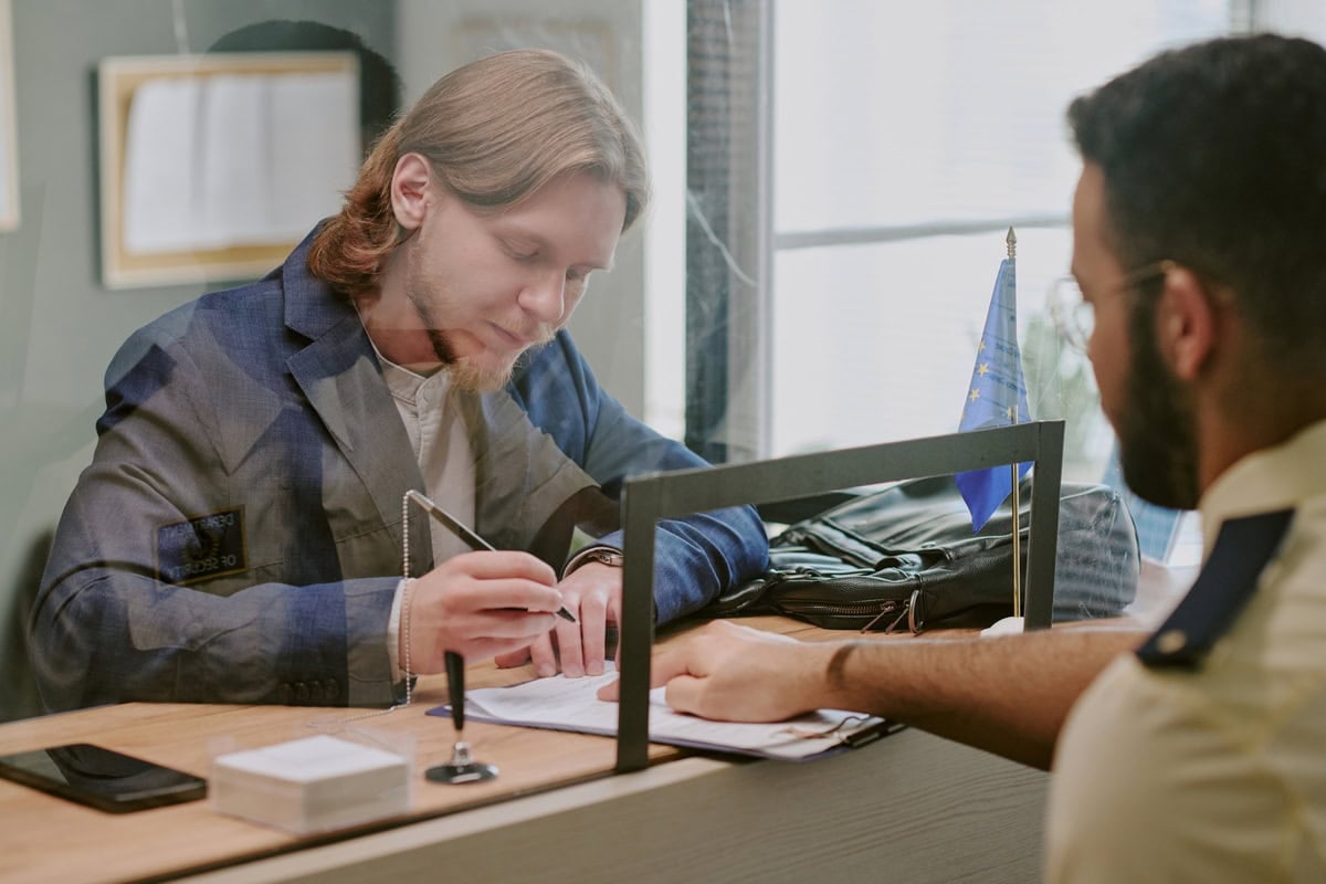 A man in a Spanish immigration office signing paperwork