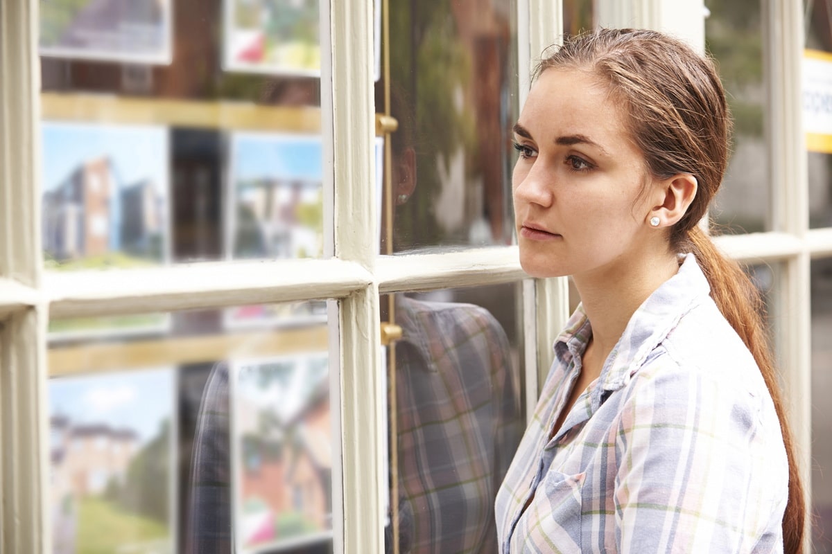 Lady looking in a real estate window wondering how to get a mortgage in Spain