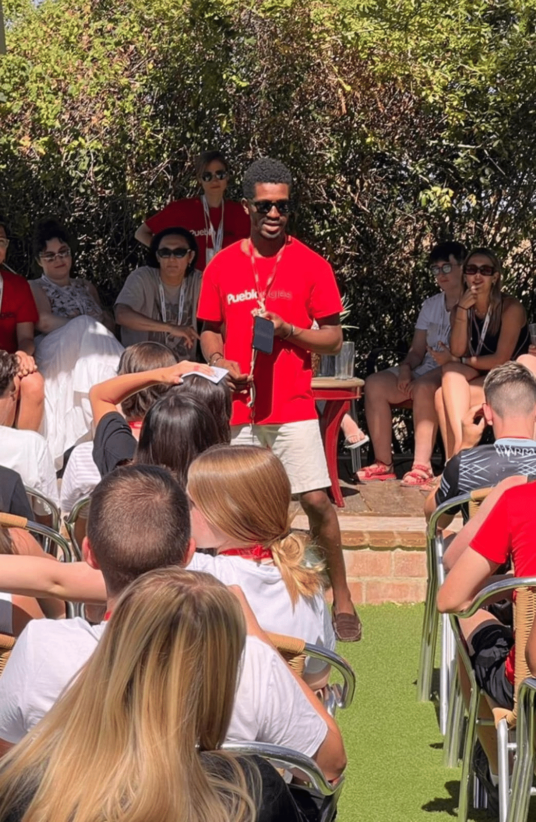 Ashton Dorminvil in a red shirt standing in front of a group of people