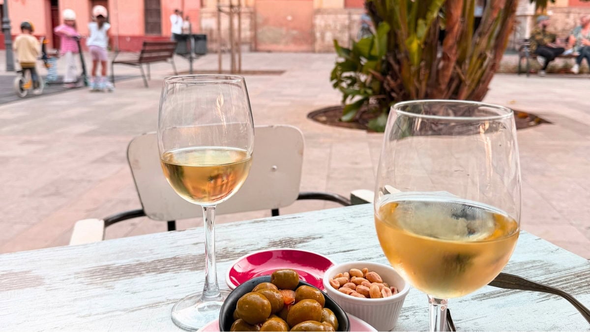 Wine at a restaurant with children on scooters in the background.  A family thiriving in Spain
